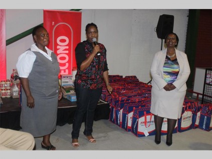 Engedzani Dzebu (Masscash, sustainability officer) is flanked by Mashabashaba Mokoela (Mmaphatla Primary School) and Rakgadi Moselekwa (Makeketela Primary School). Dzebu is handing over stationery packs for the schools' gr. R 2015 learners.