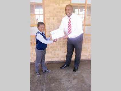 Mike Mashaba (Esau Mosedame Primary School, principal) presents a certificate of excellent to the top gr. 7 learner, Keitumetse Seshibe.